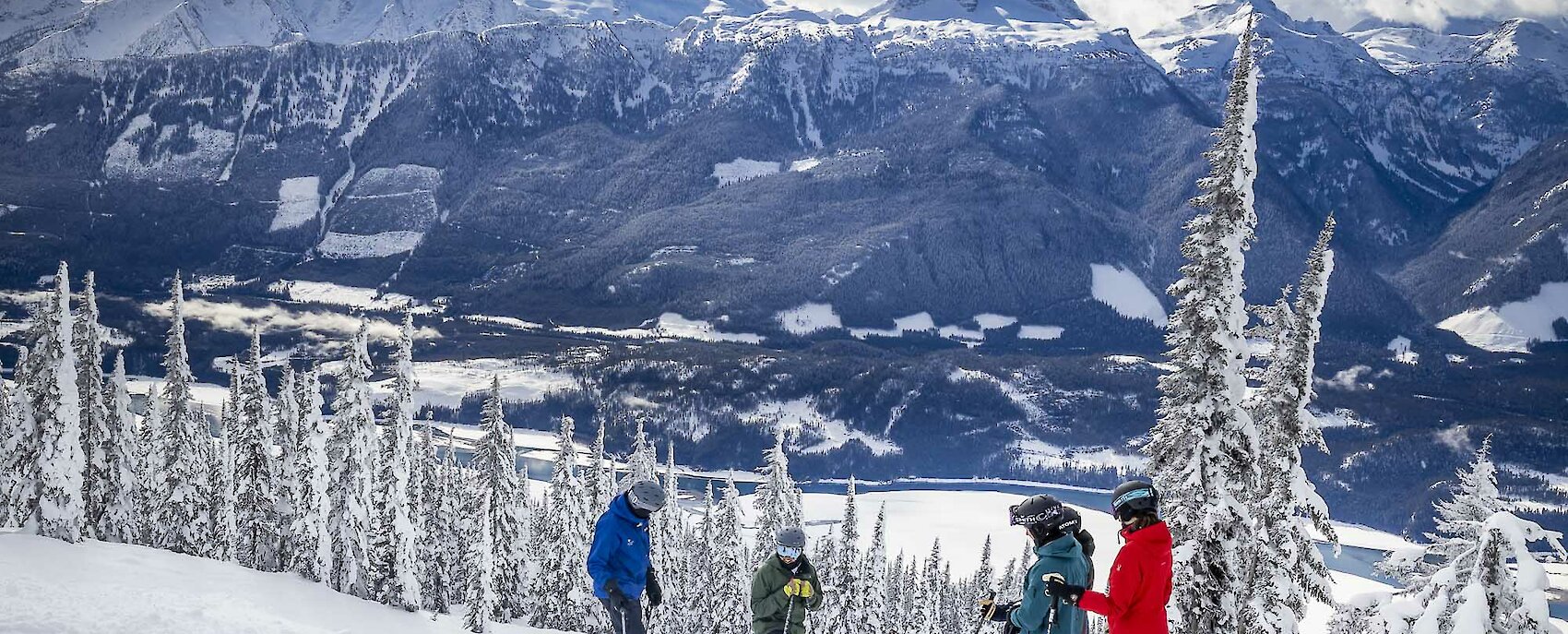 Group ski lesson on snowy mountain slopes with scenic view of snow-covered peaks and valley