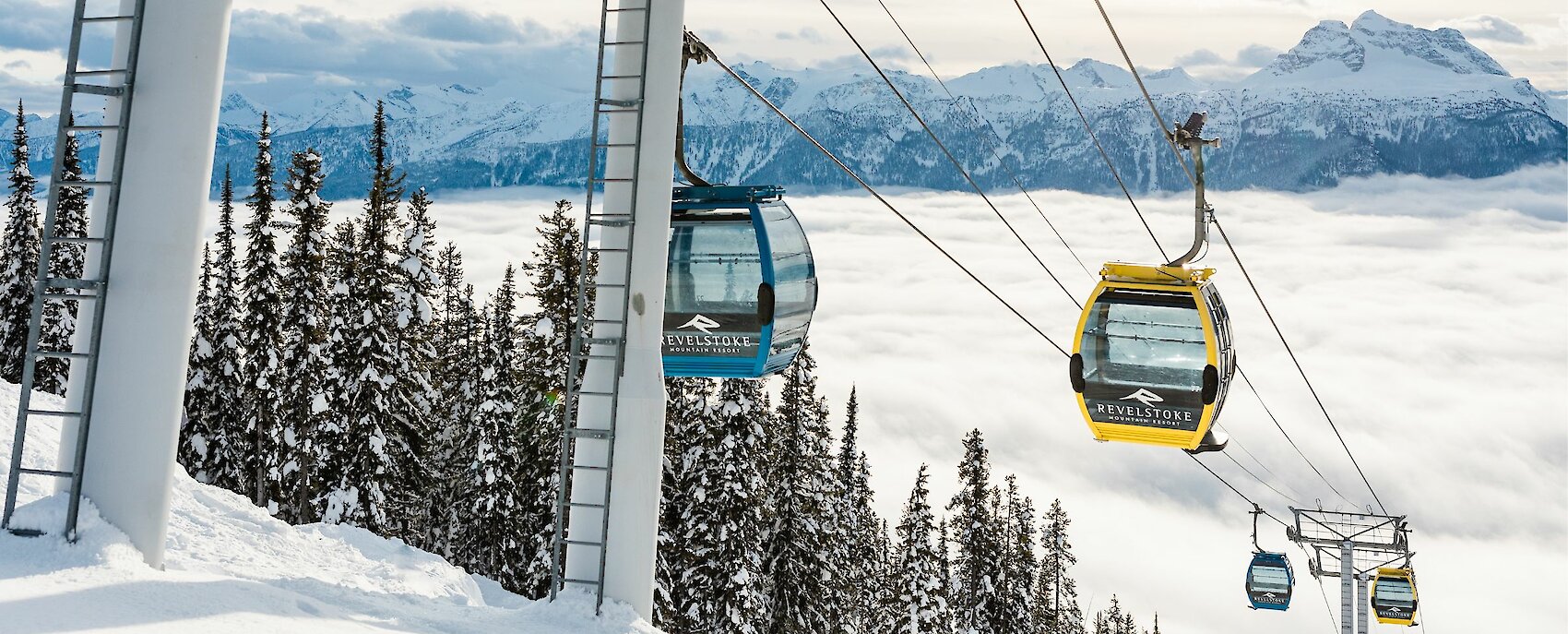 Revelstoke gondola climbing above a sea of clouds with snowy alpine trees and mountain peaks in the background