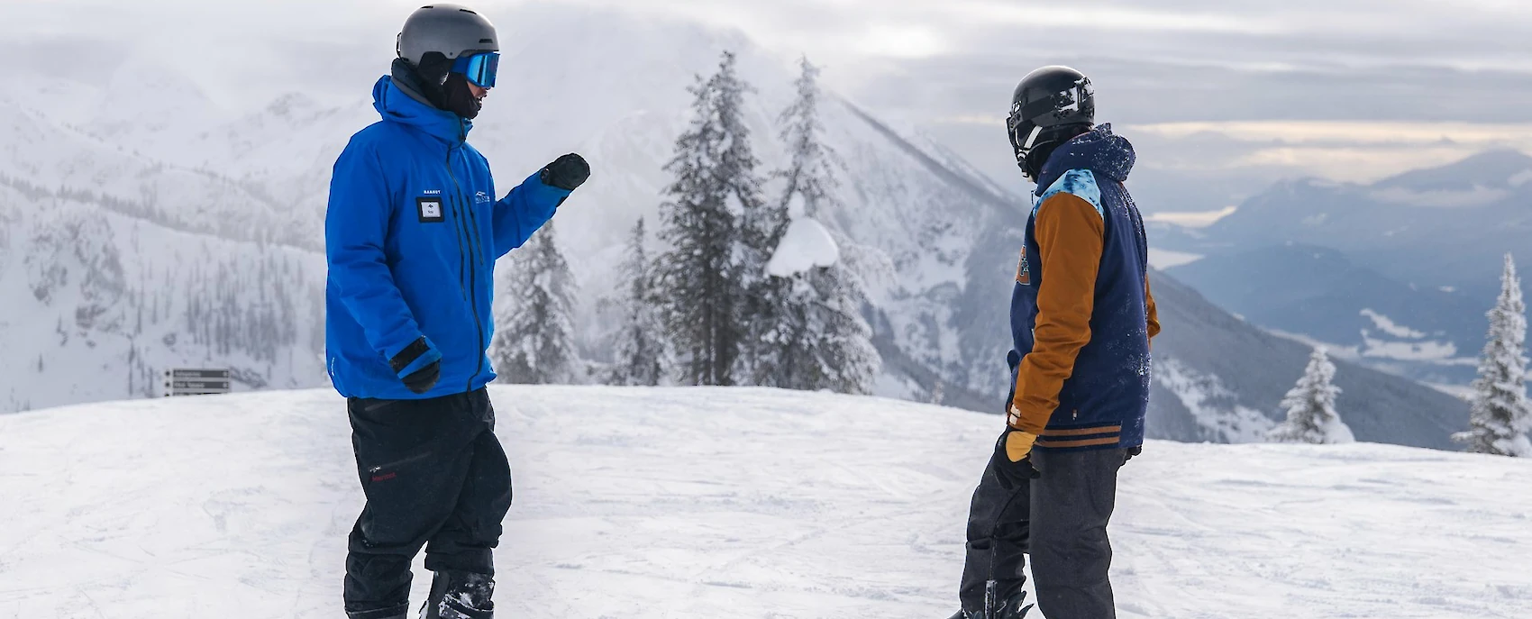 Snowboarders taking a lesson on a snowy mountain with scenic alpine views in winter