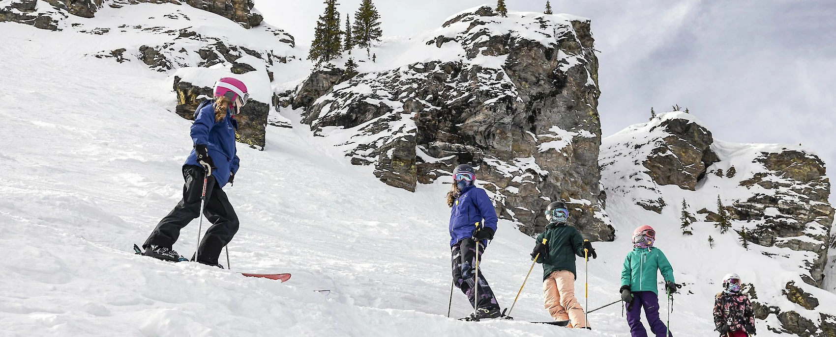 Children skiing in snowy mountains during a snow school lesson