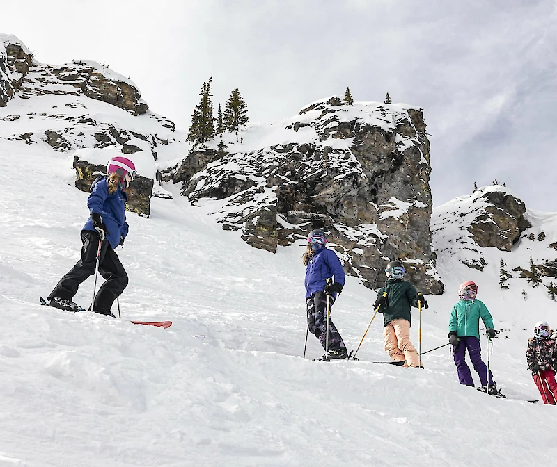 Children skiing in snowy mountains during a snow school lesson