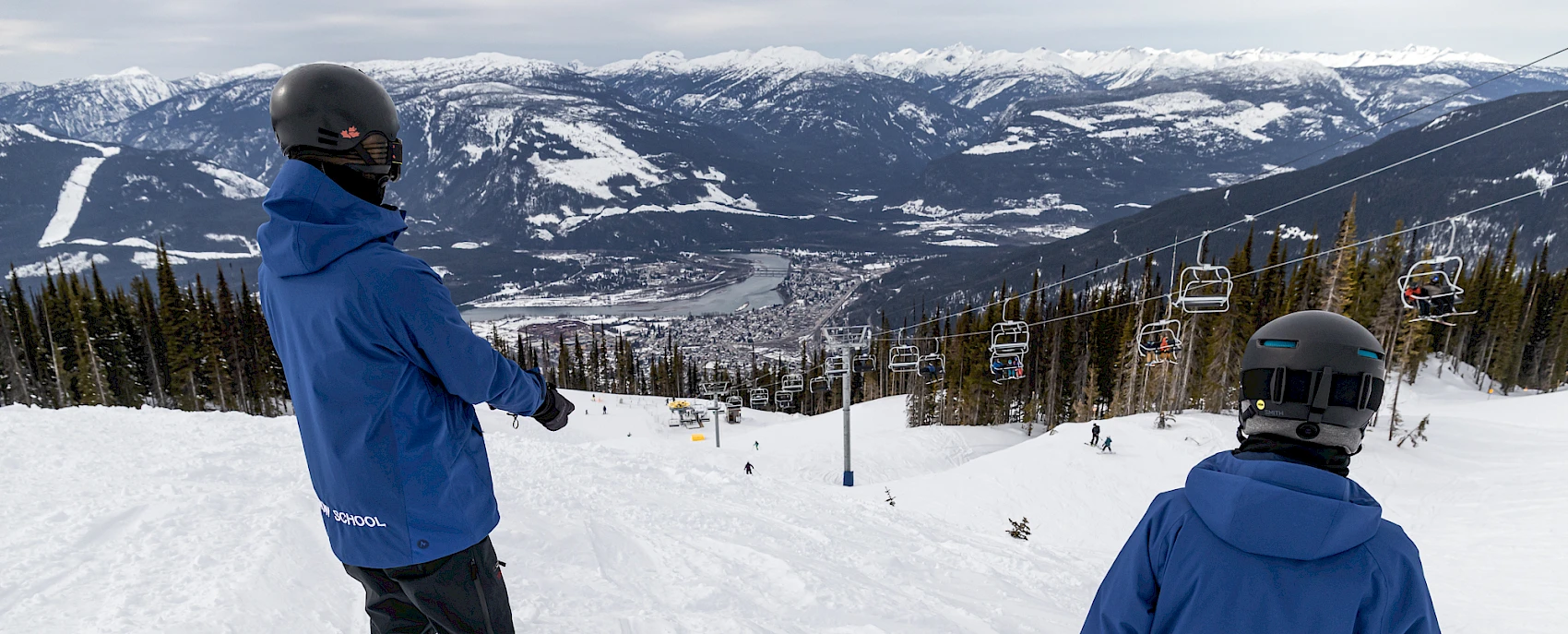 Snowboard instructor and student on a slope with a mountain view