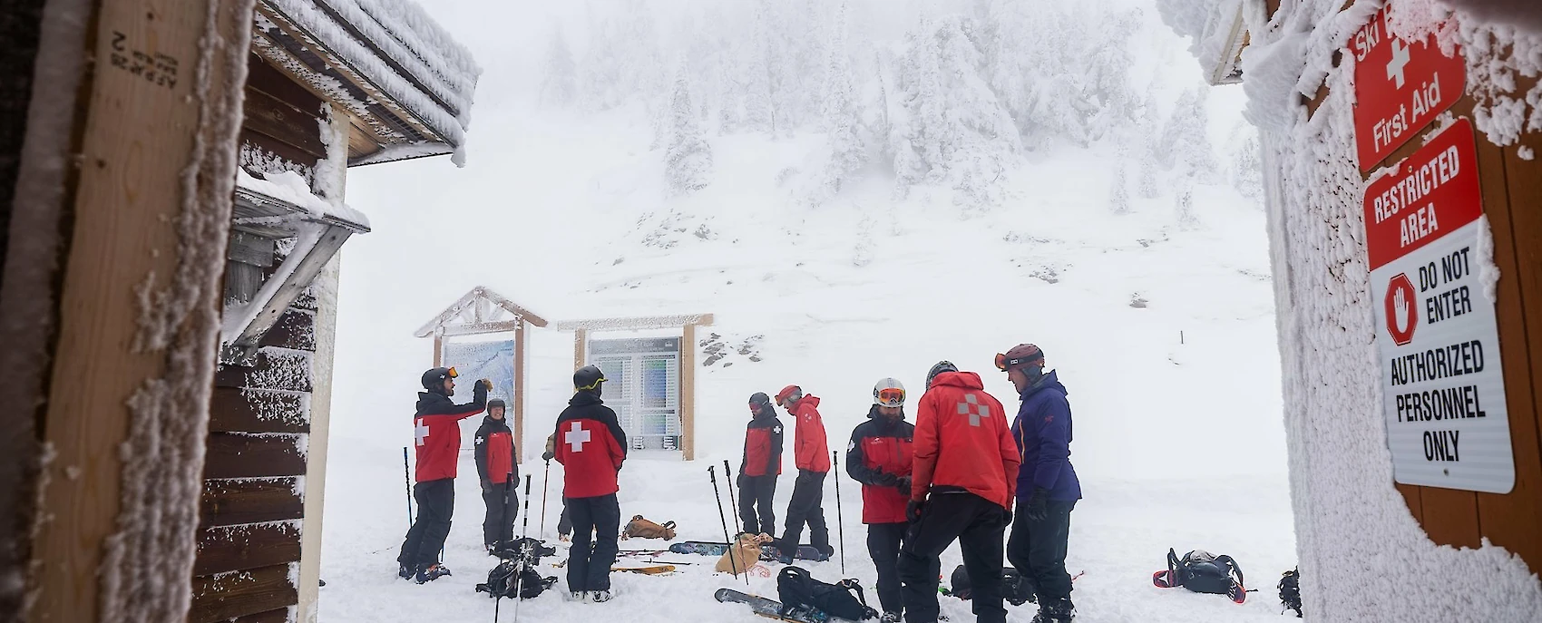 Ski patrol team preparing for winter in deep snow at a first aid station